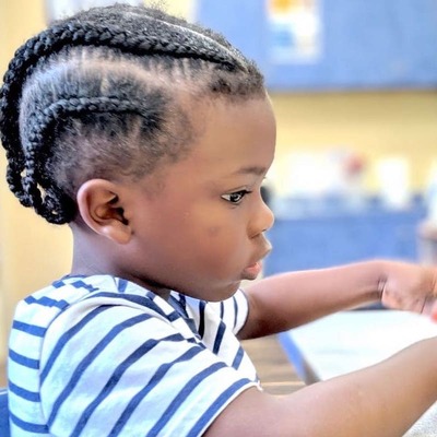 A toddler sitting by a table focused on a school task